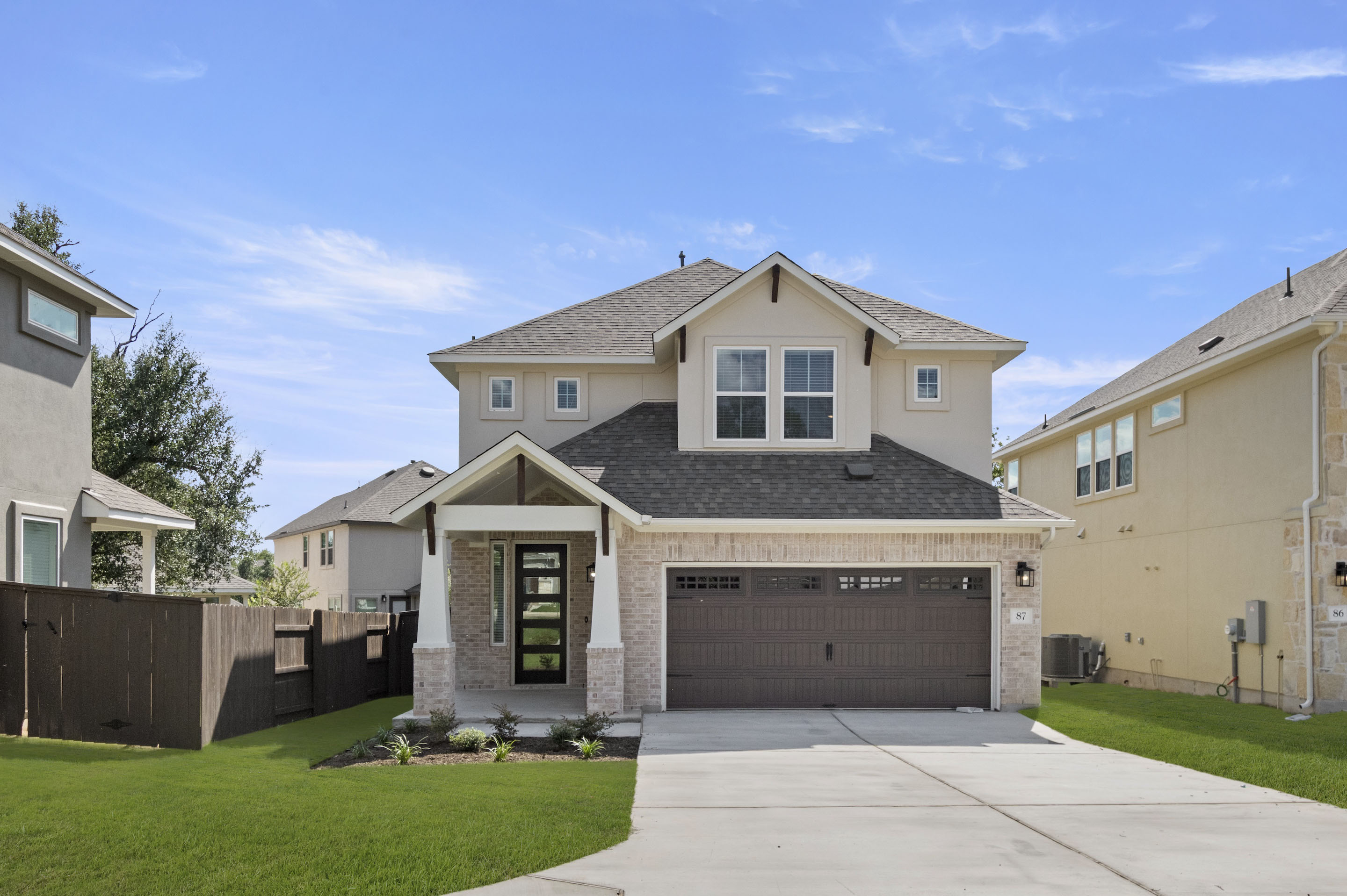 Front exterior of two-story home with a brown garage door and brown front door and green landscape.
