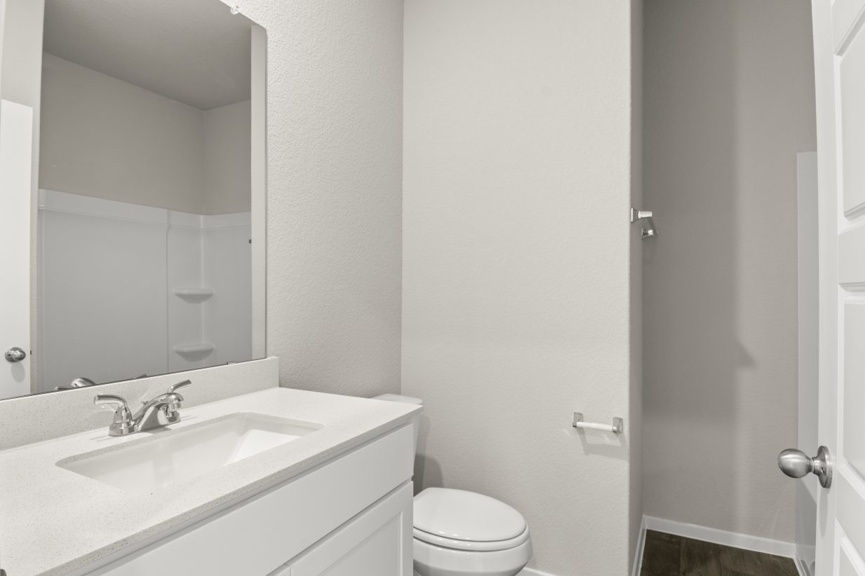 Image of bathroom with white vanity and cabinets, toilet, and bathtub