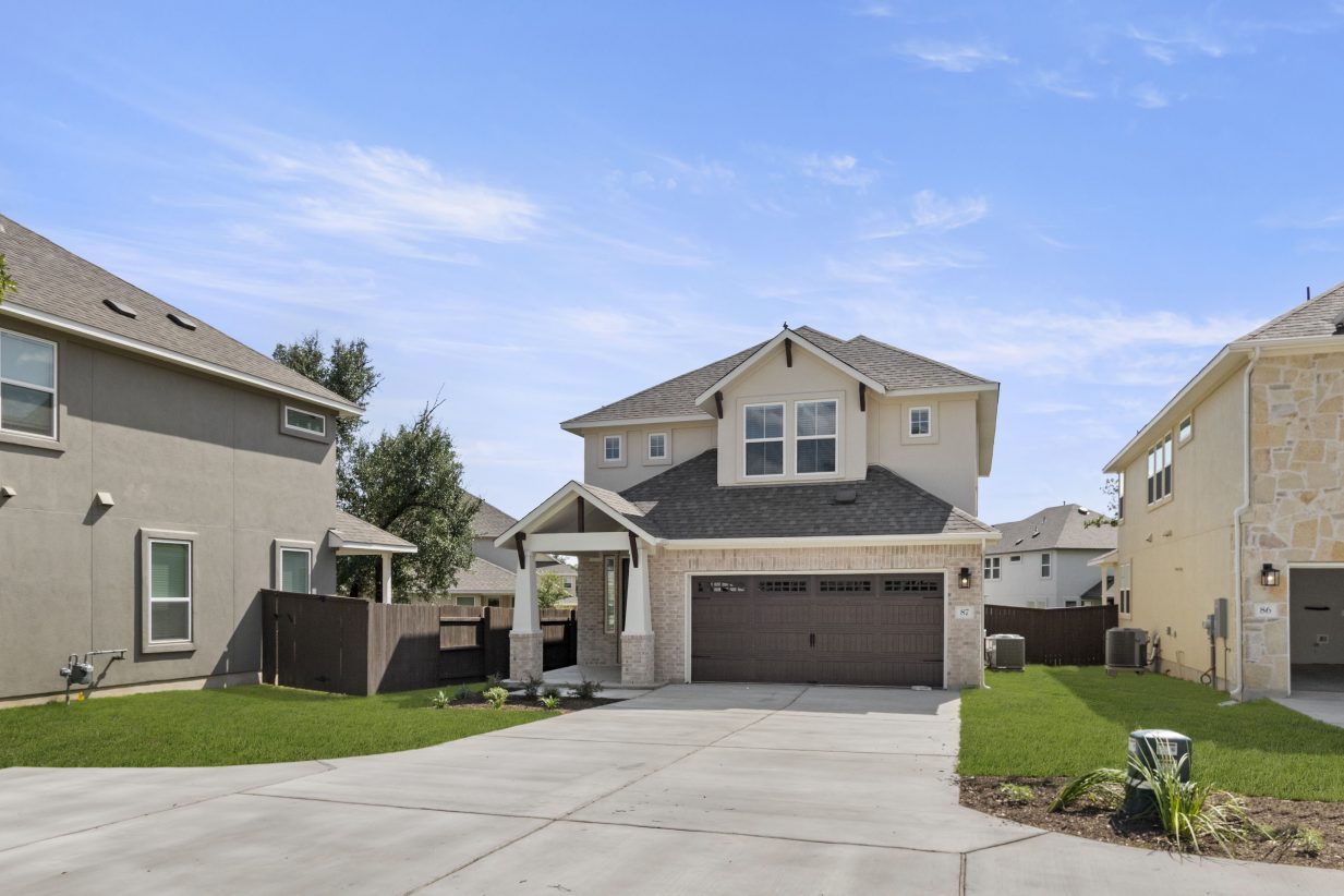 Front exterior of two-story home with a brown garage door and brown front door and green landscape.