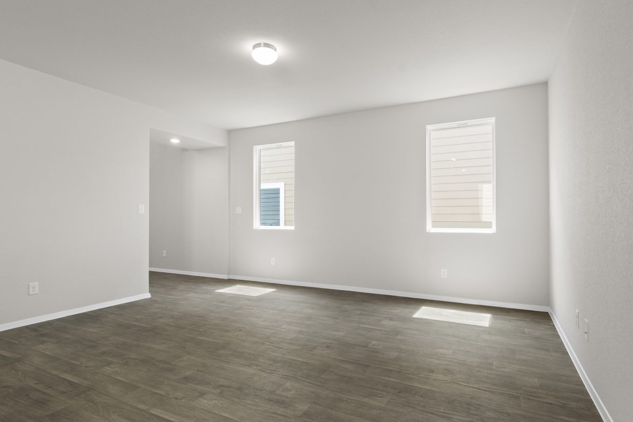 Interior image of the living room with white wall, windows, and vinyl wood-like flooring.