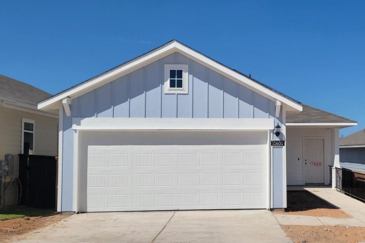 Image of front exterior of one story blue home with white trim and garage