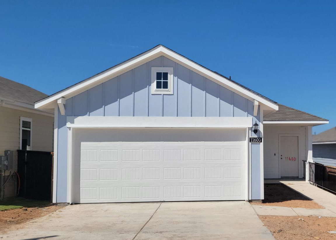 Image of front exterior of one story blue home with white trim and garage