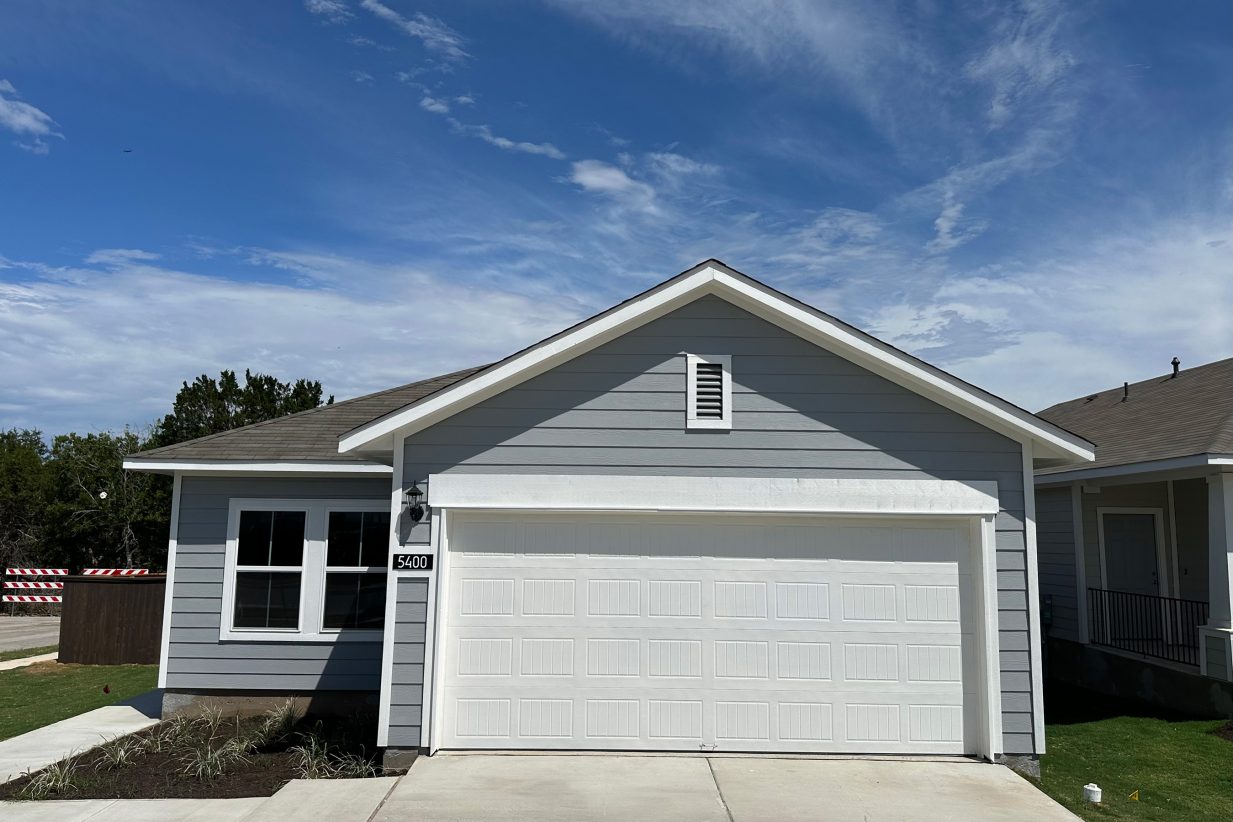Exterior of one story slate grey home with white traim and garage door with driveway and sky
