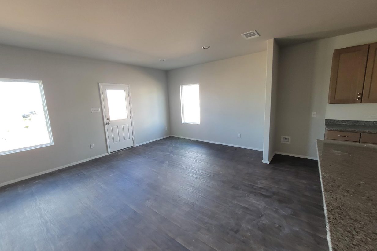 Image of home living area with wood look floor, white walls, and windows