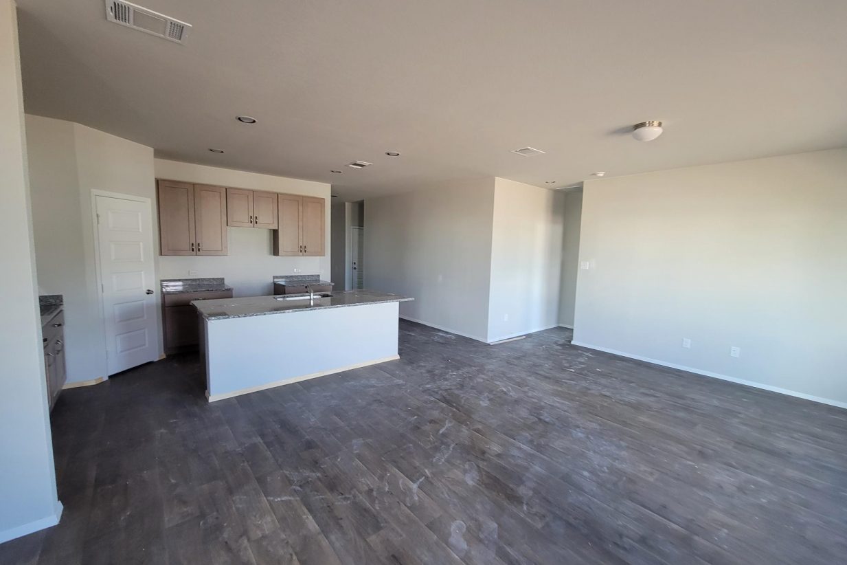 Image of home living and kitchen with wood look floor, light brown cabinets, and white walls