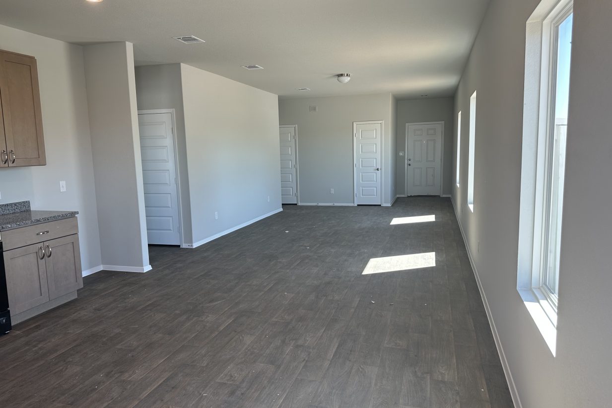Image of living spaces looking toward the front door with windows and wood-look vinyl floor