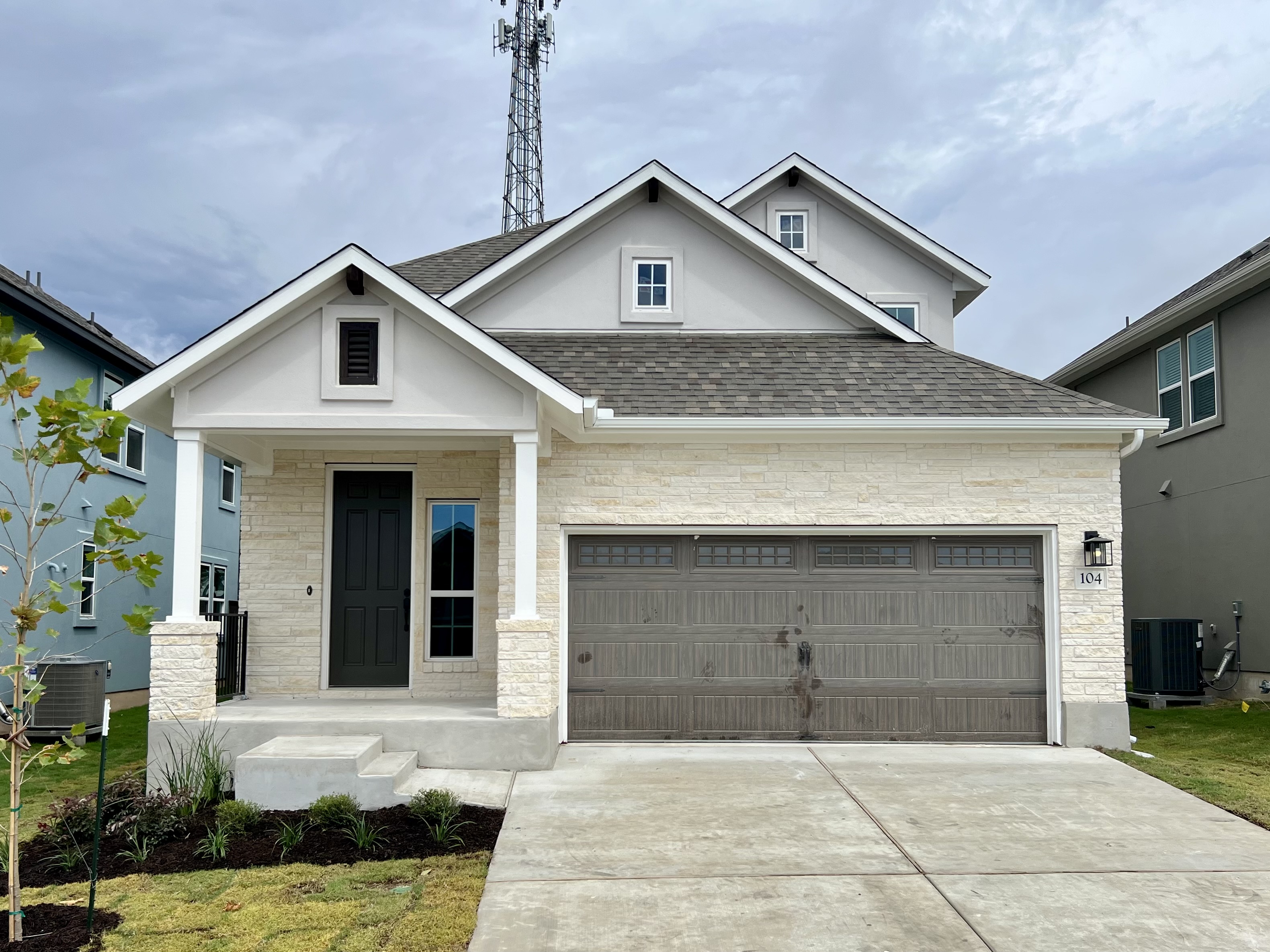 Front exterior of two-story house with a brown garage door with a driveway and green landscape.