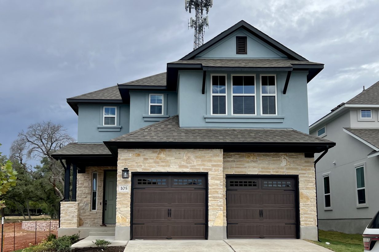 Front exterior of a blue two-story house with a double brown garage and driveway.