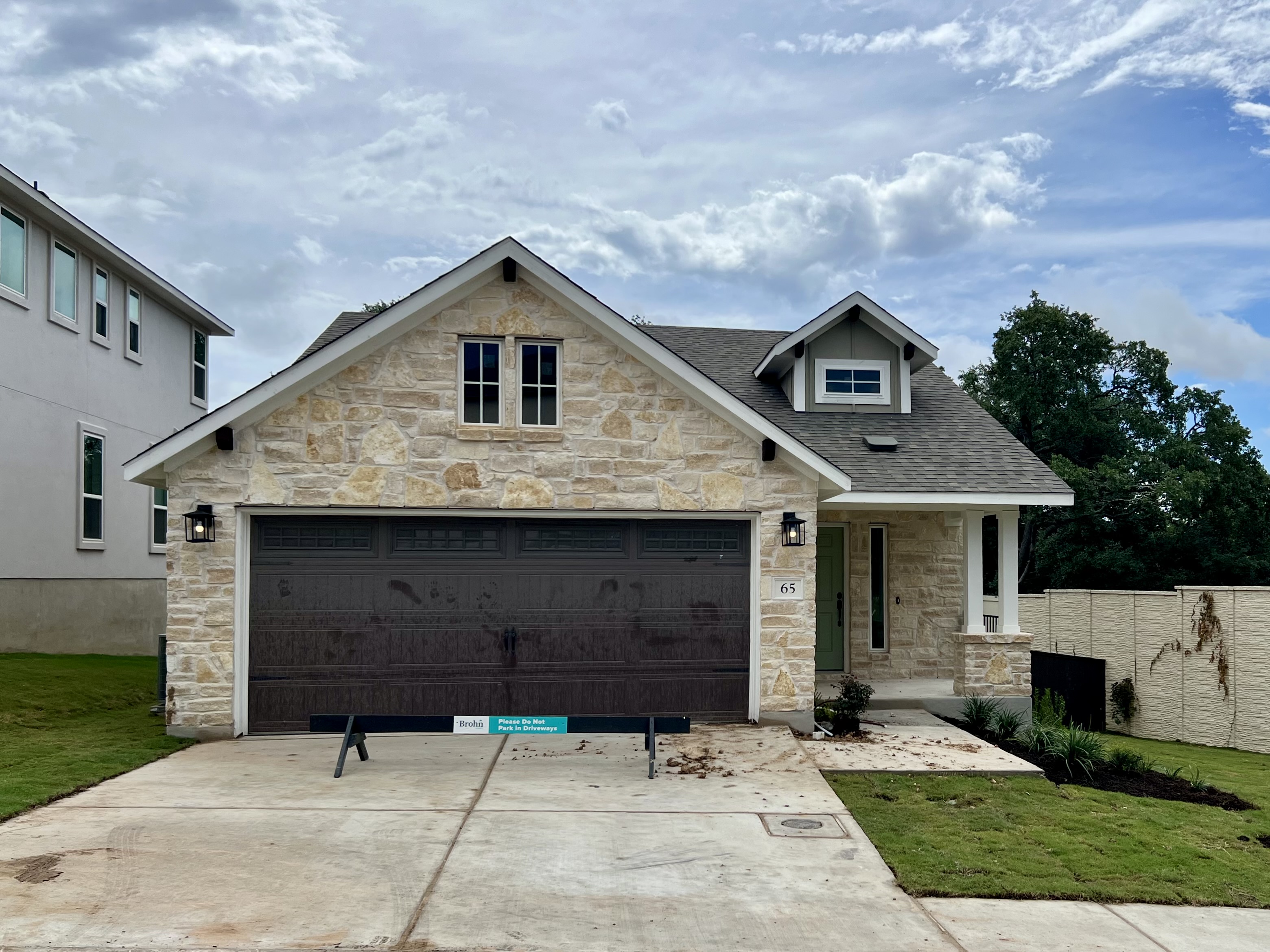 Front exterior image of brick house with brown garage door, driveway, and green landscape.