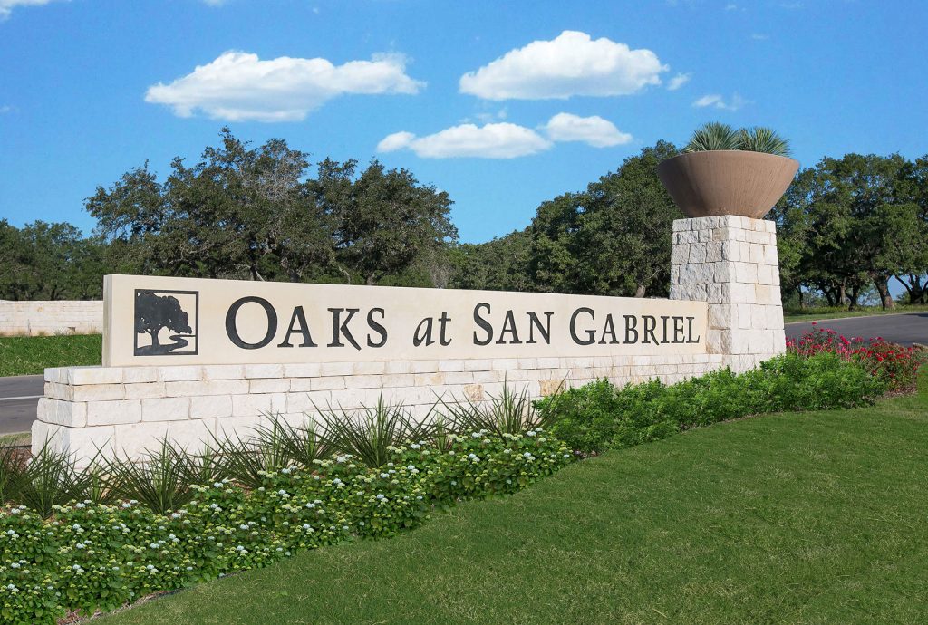 Image of community monument for Oaks at San Gabriel with grass, landscaping, trees, and sky